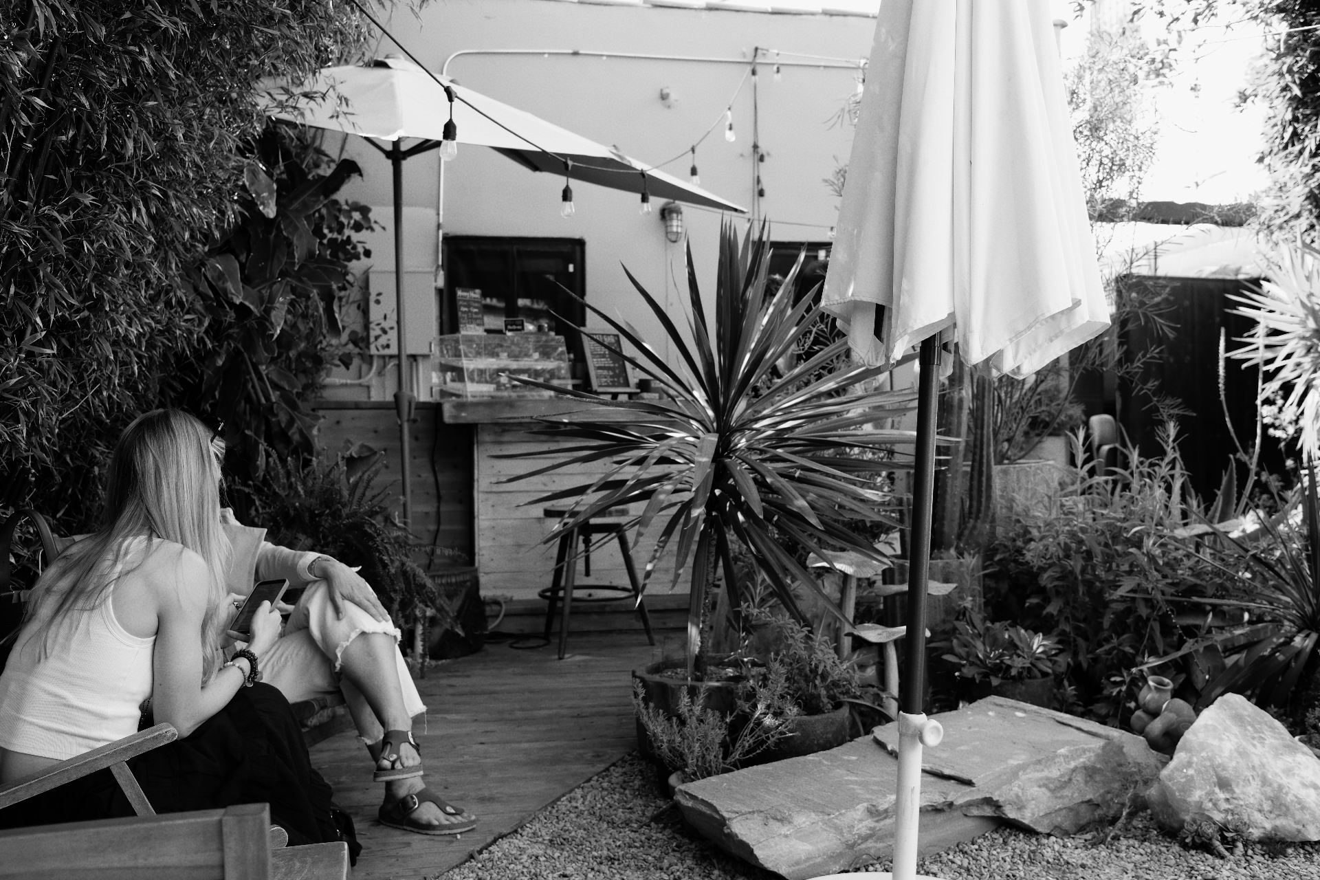Two women sitting in a plant-filled courtyard